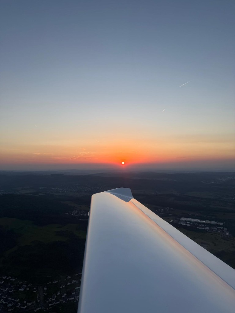 Blick über die Tragfläche im glühenden Abendhimmel während des Sonnenuntergangs