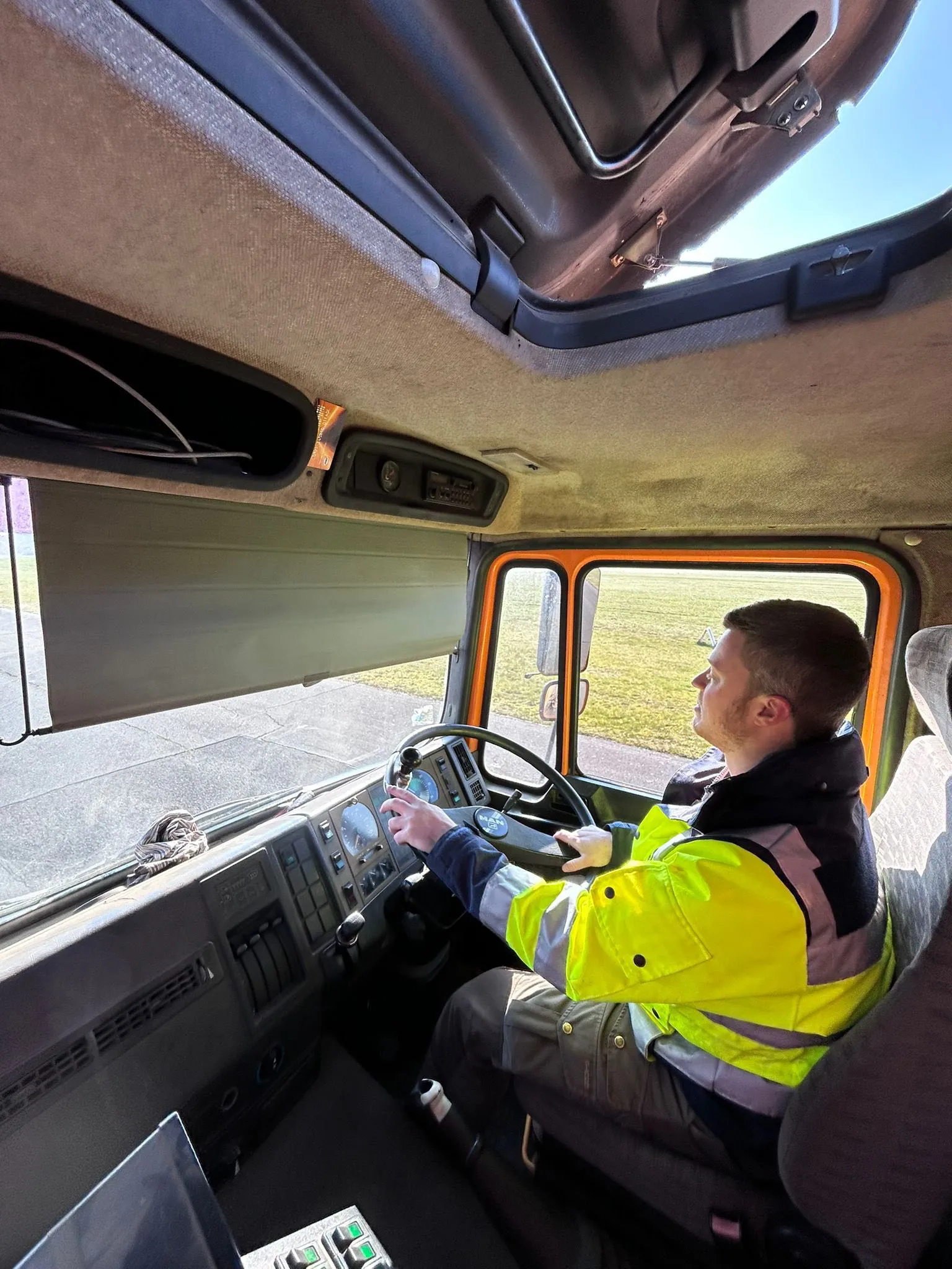 Fahrer in der Kabine des MAN-Kehrwagens mit Blick auf Rollweg und Vorfeld