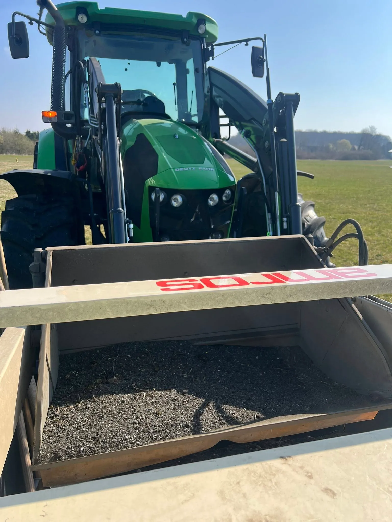 Traktor mit angefülltem Kehrgutbehälter – aufgesammeltes Material von Piste und Rollweg